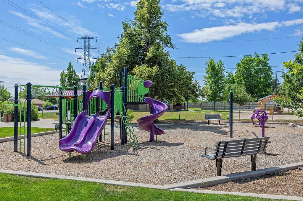 A playground with a purple slide and a green swing set.