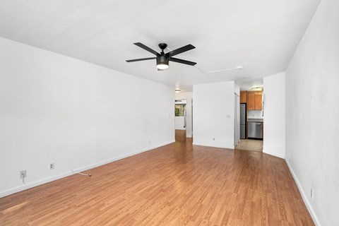 A room with a ceiling fan and wooden flooring.