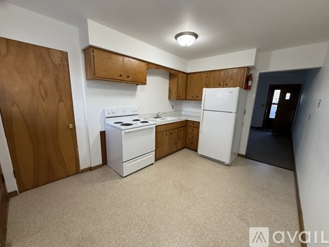 A kitchen with white appliances and wooden cabinets.