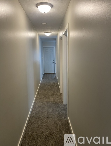 A long hallway with carpeted floors and white walls.