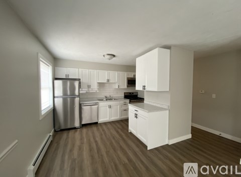 A kitchen with white cabinets and a stainless steel refrigerator.