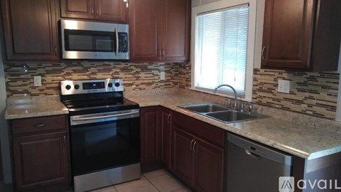 A kitchen with brown cabinets and a granite countertop.