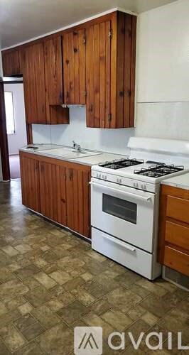 A kitchen with a white stove and wooden cabinets.