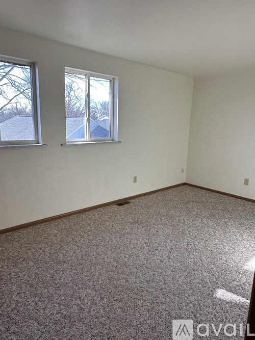 A room with two windows and a carpeted floor.