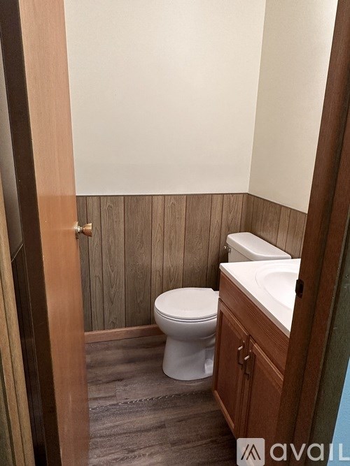 A white toilet sits in a bathroom with wood paneling.