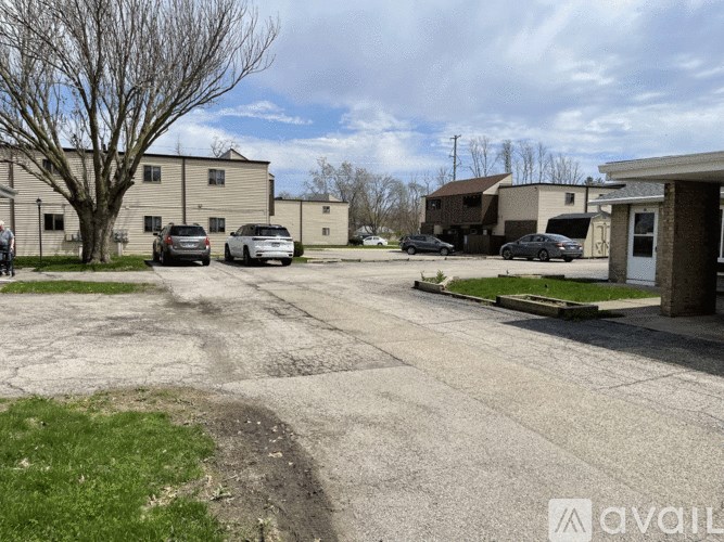 A parking lot with several cars and buildings in the background.