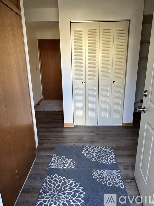 A hallway with a rug and a door with a handle.