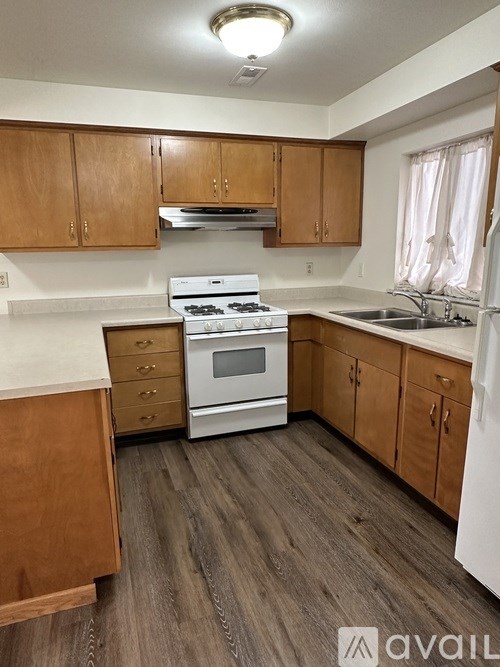 A kitchen with wooden cabinets and a white stove top oven.