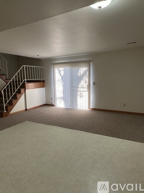 A spacious room with a staircase and a sliding glass door.