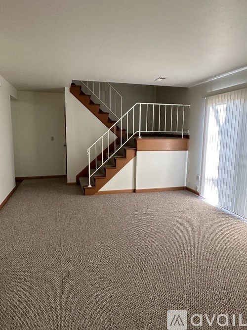 A carpeted room with a staircase and a window.