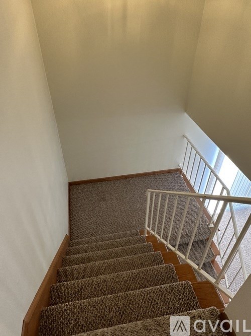 A staircase with a carpeted runner and white railing.