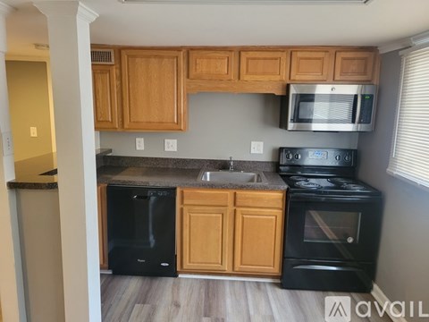 A kitchen with wooden cabinets and black appliances.