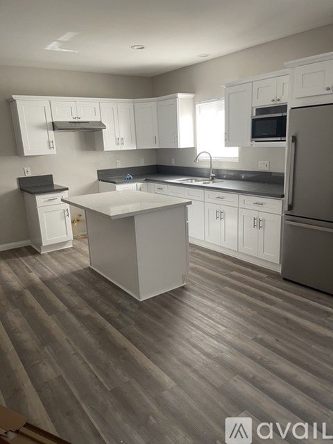 A kitchen with white cabinets and a grey island.