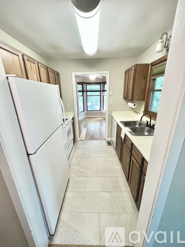 A kitchen with a white refrigerator and wooden cabinets.