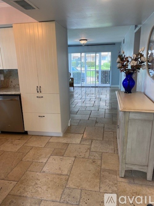 A kitchen with a tiled floor and a sliding glass door leading to a balcony.