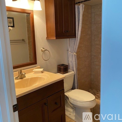 A bathroom with a toilet, sink, and mirror.