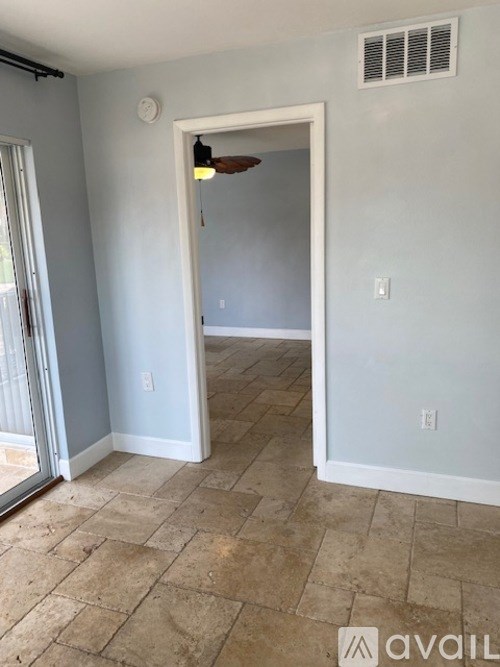 A room with a tile floor and a doorway leading to another room.