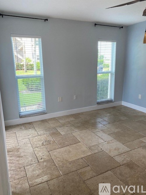 A room with tiled flooring and two windows.