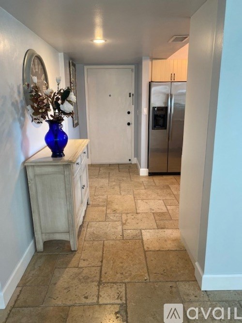 A hallway with a vase on a dresser and a framed picture on the wall.