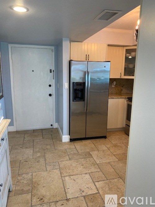 A kitchen with a tile floor and a refrigerator.