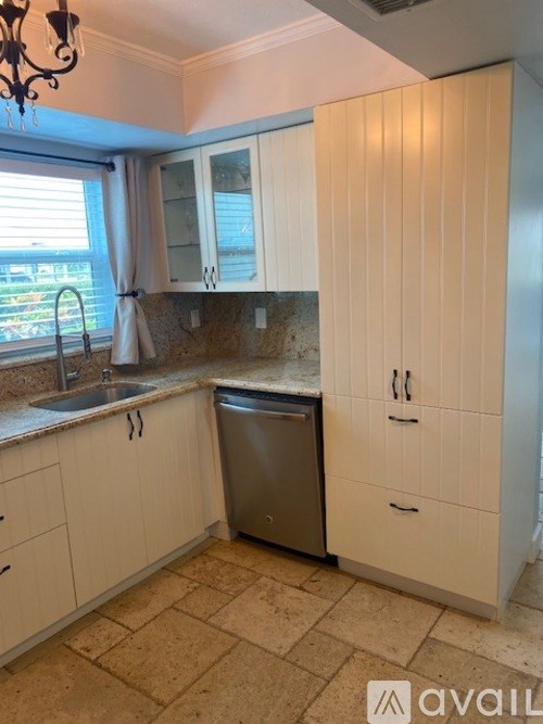 A kitchen with white cabinets and a tiled floor.