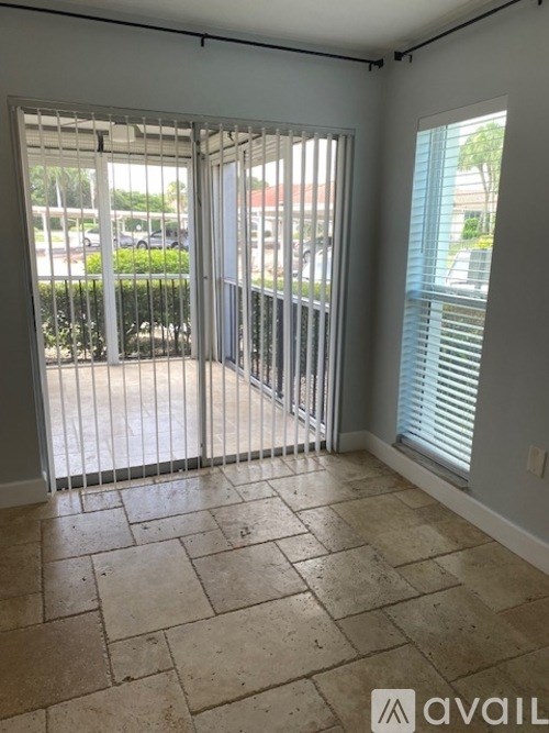 A room with tiled flooring and a sliding glass door leading to a balcony.
