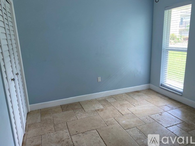 A room with a tiled floor and a window with blinds.