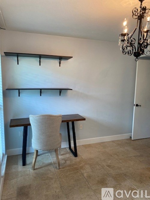 A room with a chair, table, and shelves.