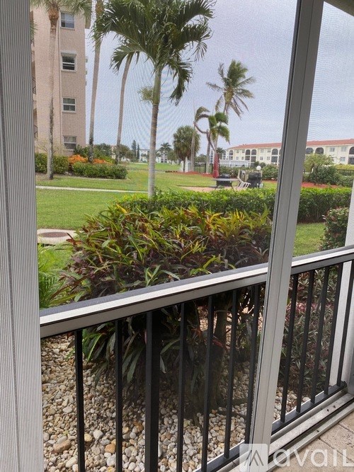A balcony with a view of a green lawn and palm trees.