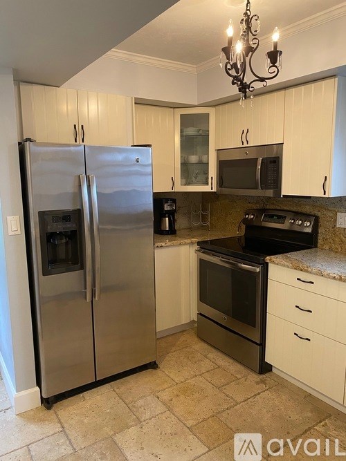 A kitchen with a silver refrigerator and black stove.