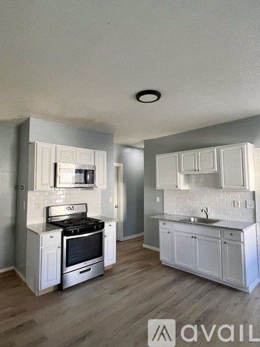 A kitchen with white cabinets and a stove top oven.