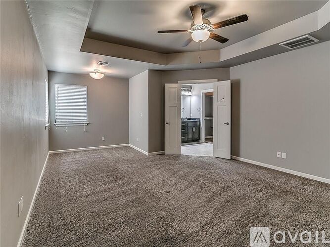 A spacious room with a ceiling fan and carpeted floor.