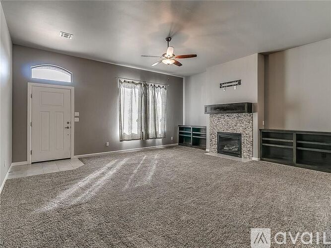 A spacious living room with a fireplace and a ceiling fan.