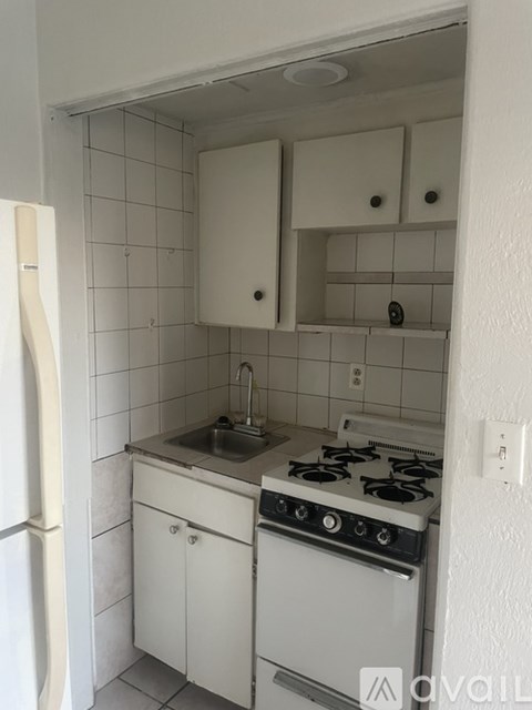 A small kitchen with a white stove and white cabinets.