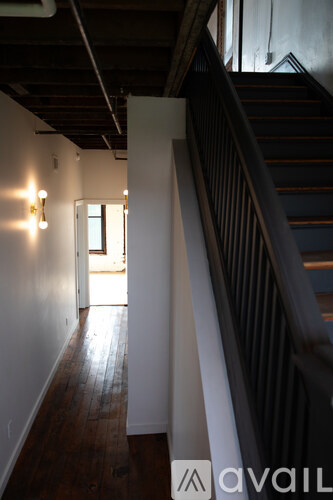 A hallway with a staircase on the right and a door on the left.