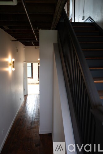 A hallway with a staircase on the right and a door on the left.