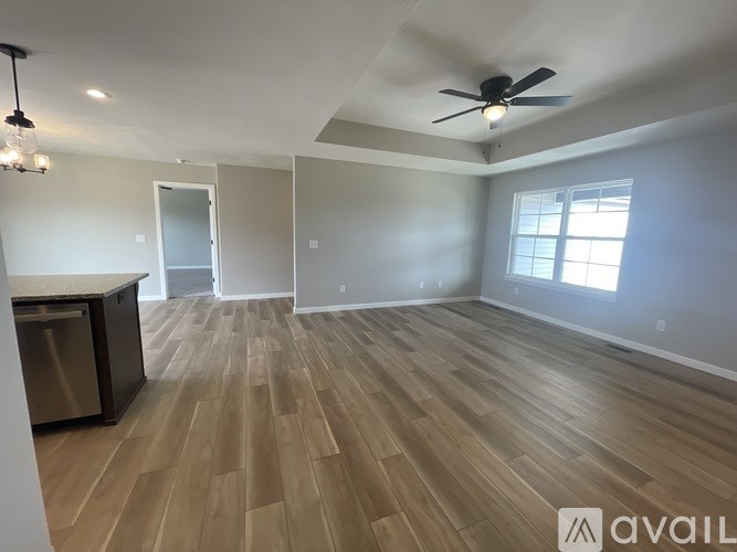 A spacious room with wooden flooring and a ceiling fan.