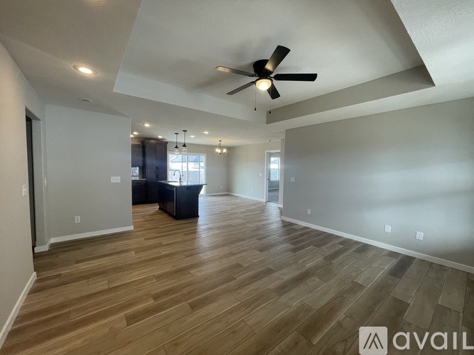 A spacious room with wooden flooring and a ceiling fan.