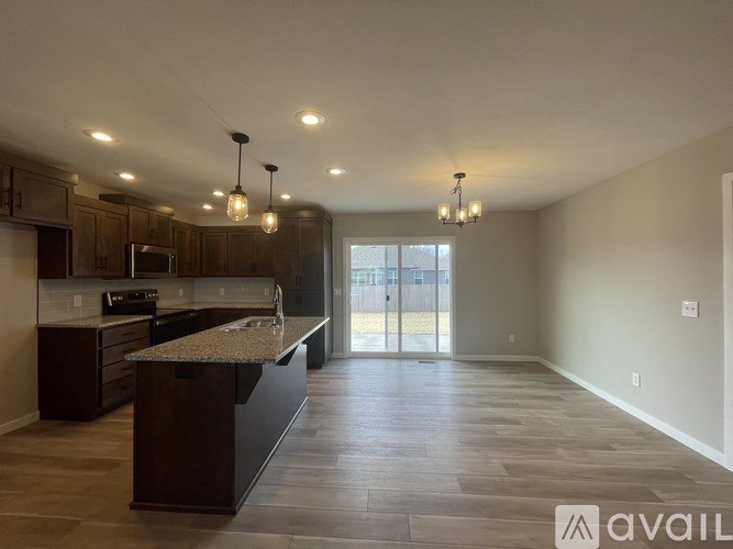 A spacious kitchen with dark wood cabinets and a granite countertop.