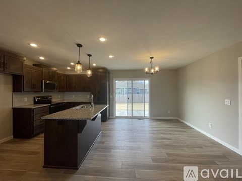 A spacious kitchen with dark wood cabinets and a granite countertop.