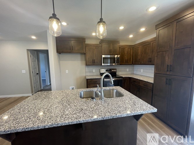 A kitchen with granite countertops and dark wood cabinets.