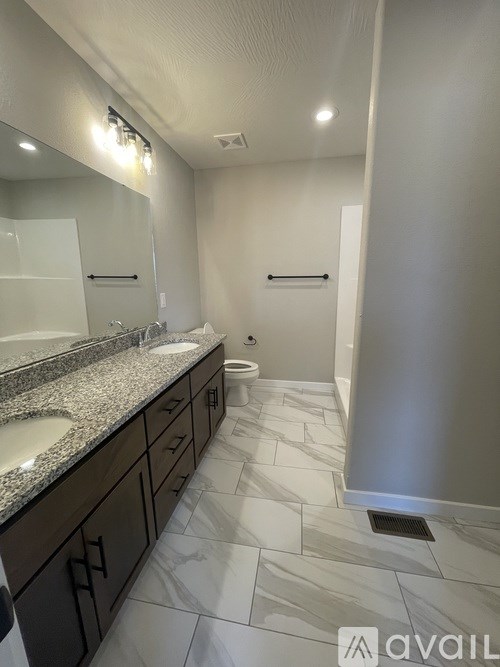 A bathroom with a marble counter top and a walk in shower.