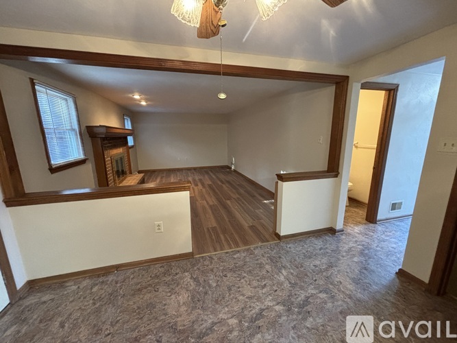 A spacious room with wood flooring and a chandelier.
