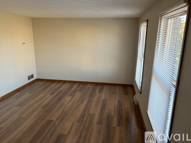 A room with wooden flooring and a window with blinds.