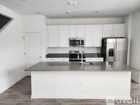 A kitchen with white cabinets and a black refrigerator.