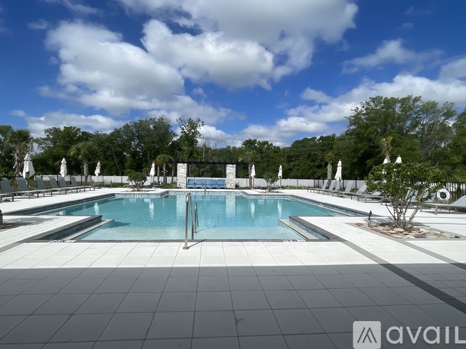 A large swimming pool surrounded by trees and a cloudy sky.