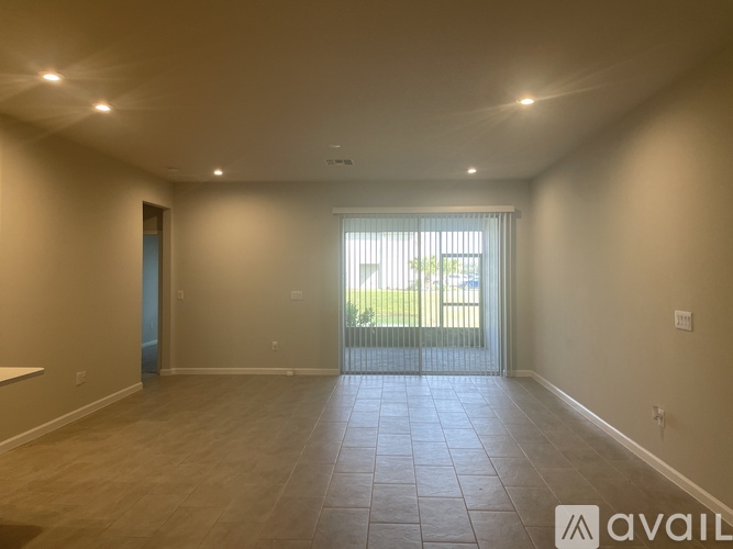 A spacious room with tiled flooring and a sliding glass door leading to a balcony.