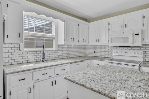 A kitchen with white cabinets and a granite countertop.