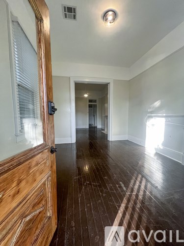 A hallway with wooden floors and a door on the left.