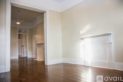 A room with wooden floors and a white door leading to another room.